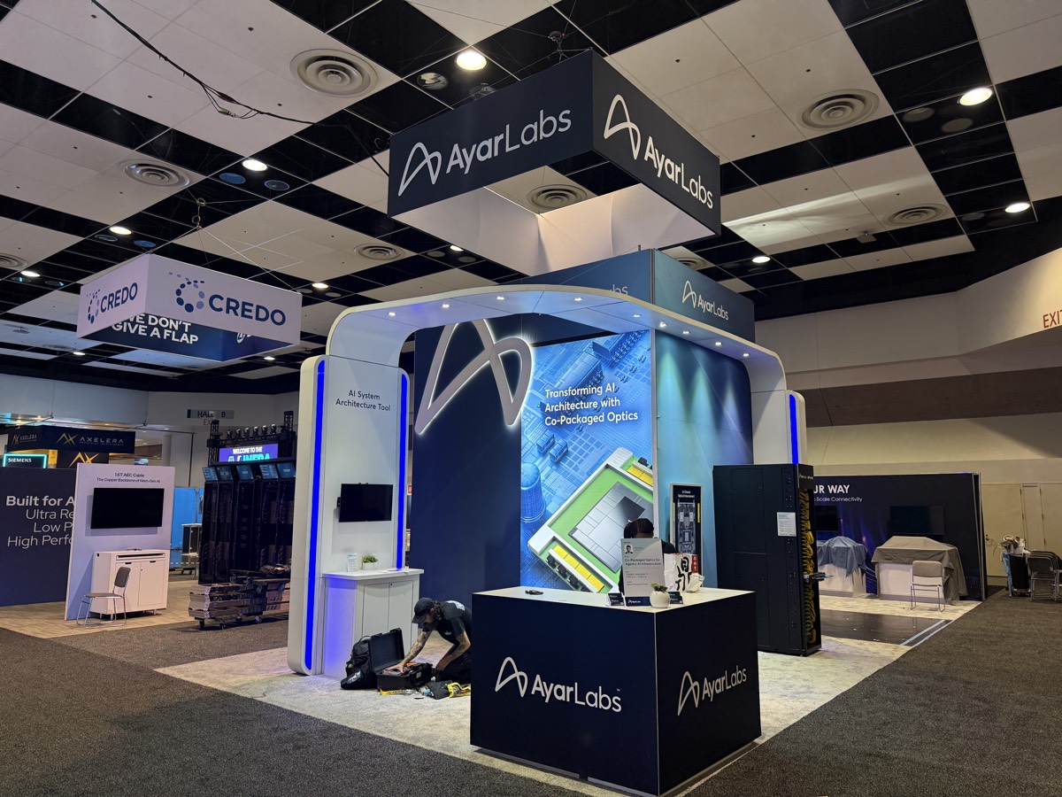 Ayar Labs island booth with hanging sign and backlit product wall, built by Art & Display